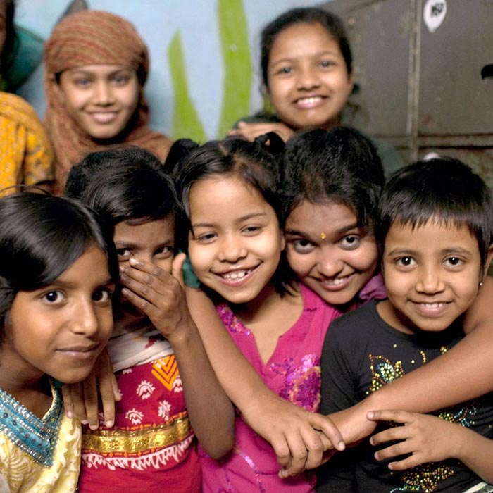 A group of young girls smiling and hugging at their Happy Homes safe house in Dhaka, Bangladesh where they get education and free healthcare