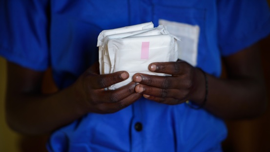A school girl holds a pack of sanitary towels.