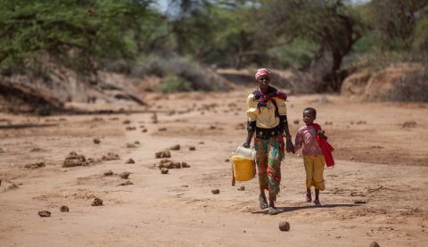 Consolata, with her daughter Elizabeth, 7, carrying jerry cans from the watering hole back to their home in Kenya.