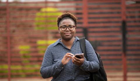 A woman holding a phone and tapping on it