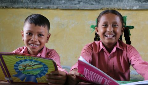 Rejina reading books with her friend at their school library in Nepal.