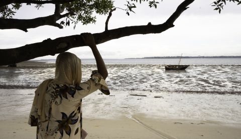 A woman standing with her back to the camera, looking out to the sea