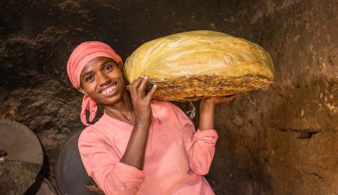 a woman in pink holding a tray of food and smiling