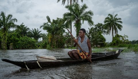 a woman paddles her canoe in the Niger Delta