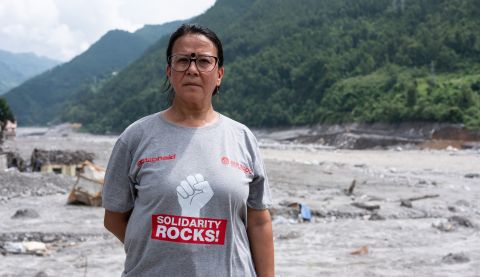 A woman standing in front of the floods destruction in Nepal