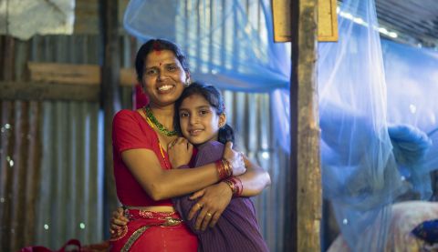 Laxmi, 35, and her daughter Kanchan, 9, stand inside their new temporary shelter constructed with support from ActionAid in a village in Rasuwa District, Nepal, July 2015
