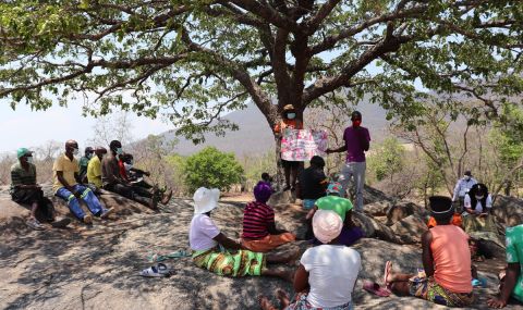 Group of men sitting under a tree during a community participation session run by volunteers in rural Zimbabwe