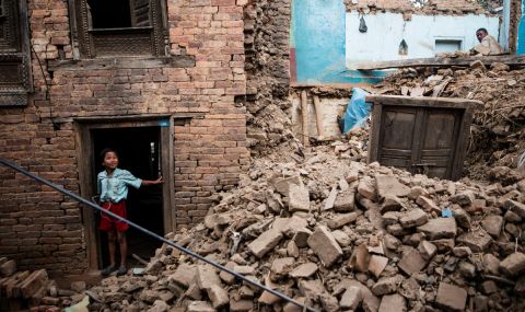 9 years old Rupak looks on as Ram bahadur and his relatives try to excavate their belongings from their collapsed house in the ruined village of Chapagaon