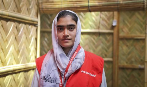 ActionAid staff worker wearing red jacket and mauve headscarf, standing in a women-friendly space insides Cox's Bazar in Bangladesh where she helps Rohingya refugees