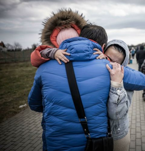 A man hugs his daughter and grandaughter after they crossed the border from Shehyni in Ukraine to Medyka in Poland.