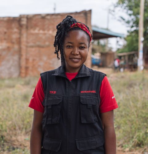 A woman in ActionAid vest smiling at camera