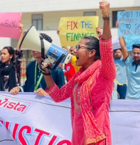 Woman with megaphone in front of crowd holding banners