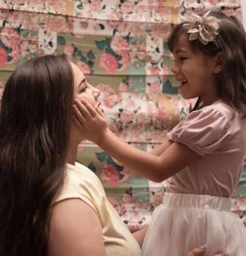 A young girl cupping her mother's face with love