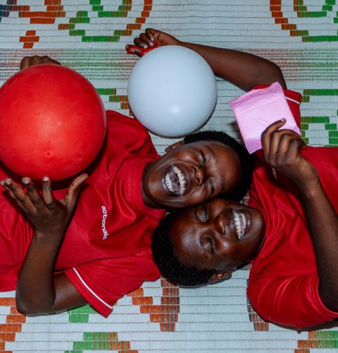 Two girls smiling and laughing playing with red and white balloons