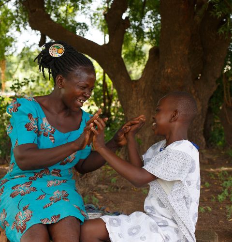 Elizabeth plays with  her daughter Eunice under a tree behind their house in Ghana's Upper West Region
