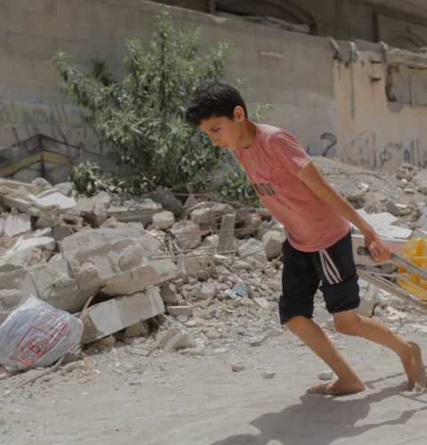 Boy wheeling water cans in Gaza
