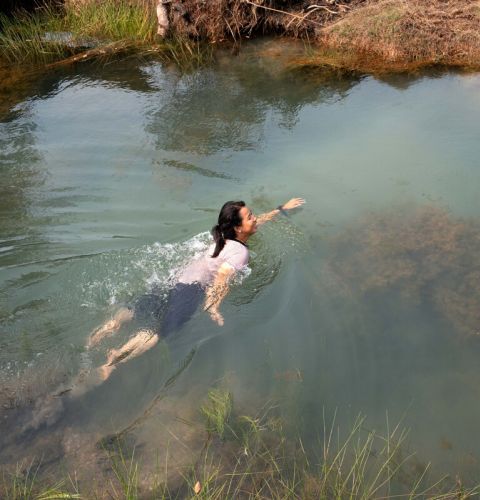 A woman swimming in the river fully clothed