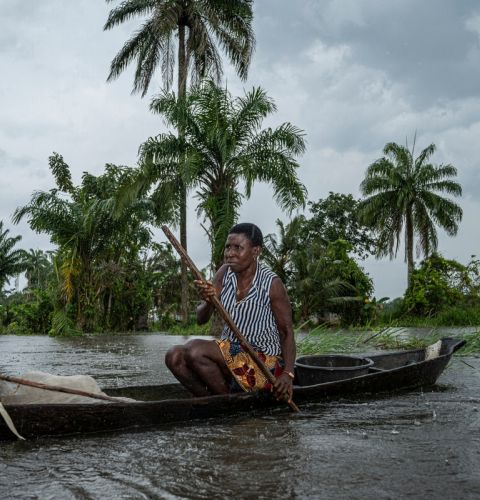a woman paddles her canoe in the Niger Delta