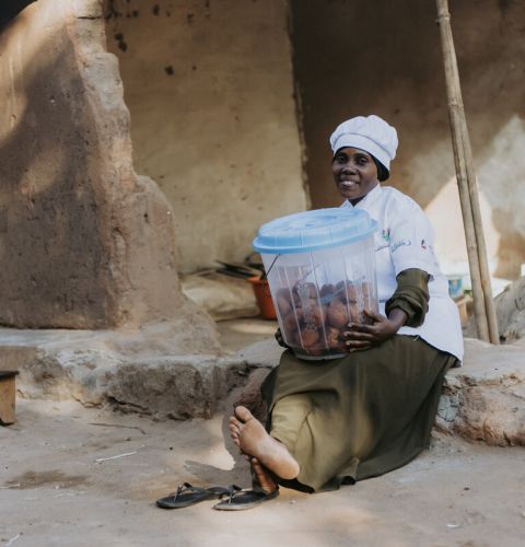 woman in a chef uniform holding a basket opr tub of food