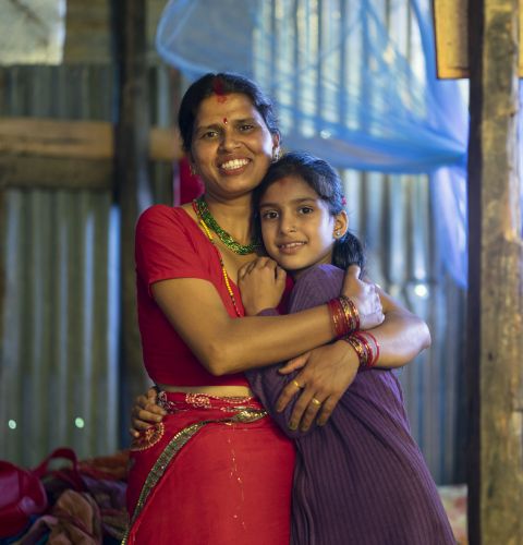 Laxmi, 35, and her daughter Kanchan, 9, stand inside their new temporary shelter constructed with support from ActionAid in a village in Rasuwa District, Nepal, July 2015