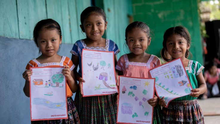 Girls hold up their pictures for her sponsor during ActionAid's annual child message collection