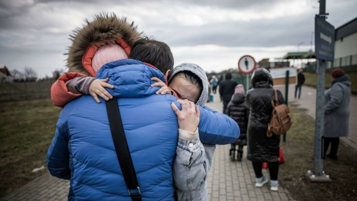 A man hugs his daughter and grandaughter after they crossed the border from Shehyni in Ukraine to Medyka in Poland.