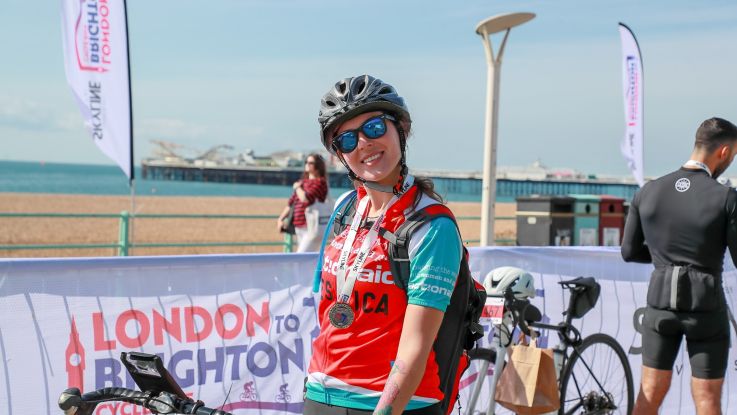 ActionAid supporter Jessica smiles after collecting her medal at the London to Brighton Cycle, 2024.