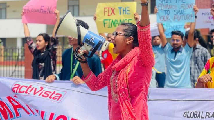 Woman with megaphone in front of crowd holding banners