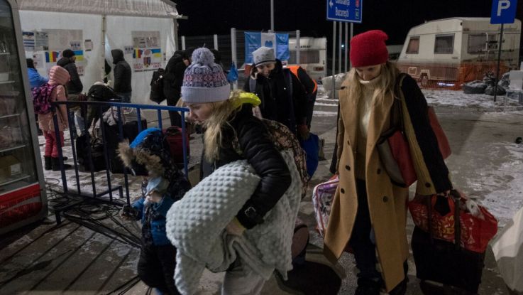 Women and children in winter clothing carrying bags and belongings