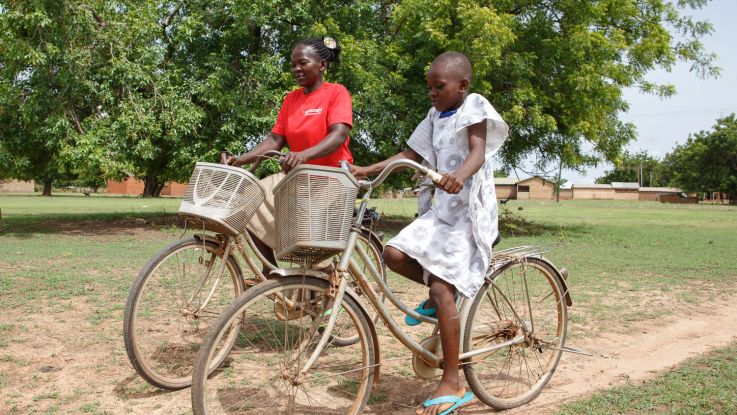 Elizabeth and her daughter Eunice ride bicycles in their community in the Upper West Region, Ghana.