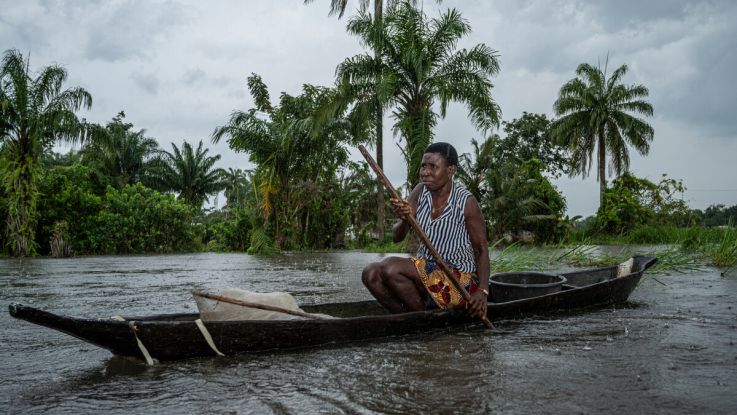 a woman paddles her canoe in the Niger Delta