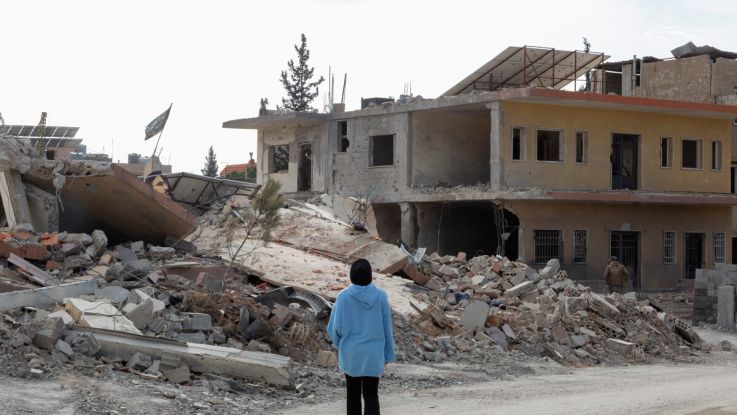 A woman with her back to camera looking at the destruction in Lebanon.