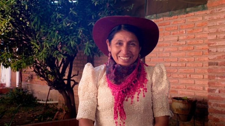 A Bolivian woman smiling to camera in a red hat