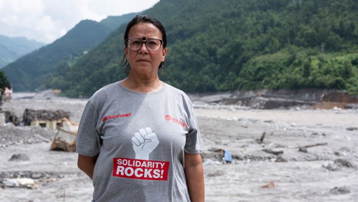 A woman standing in front of the floods destruction in Nepal