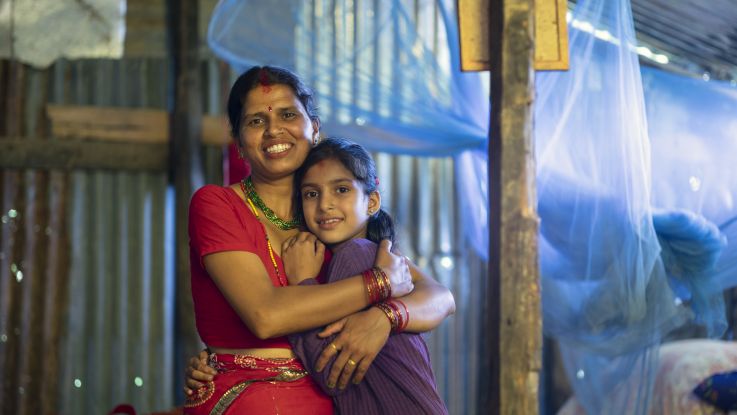 Laxmi, 35, and her daughter Kanchan, 9, stand inside their new temporary shelter constructed with support from ActionAid in a village in Rasuwa District, Nepal, July 2015
