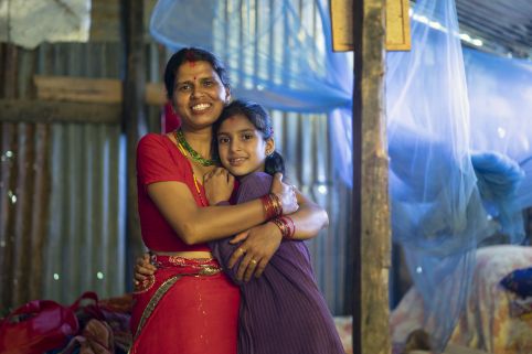 Laxmi, 35, and her daughter Kanchan, 9, stand inside their new temporary shelter constructed with support from ActionAid in a village in Rasuwa District, Nepal