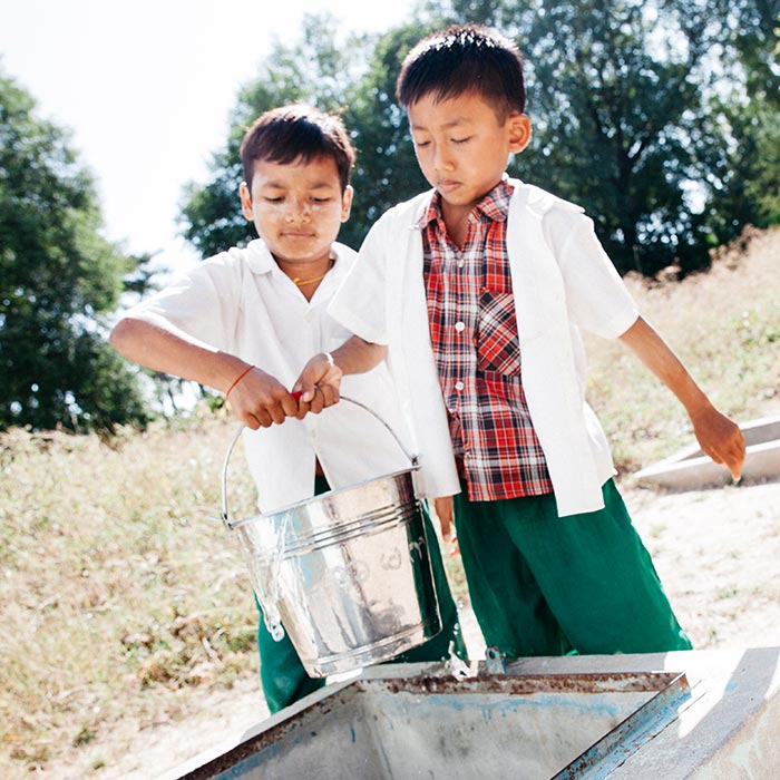 Two boys Chit Phyo, 8, wearing checked shirt and Hein Thus, 9, collect water for their school from a in a village in the Dry zone (Magway Region), Myanmar(Burma).